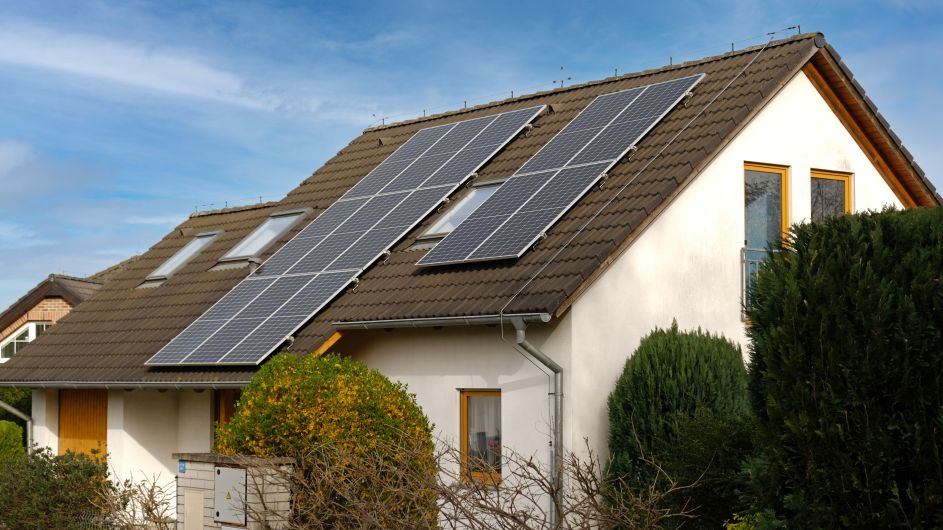 Energy-efficient house with solar roof panels and outdoor patio.
