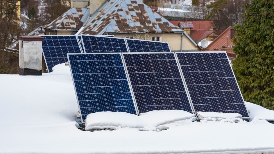 Snow-covered rooftop with solar panels showing how solar panels work in winter
