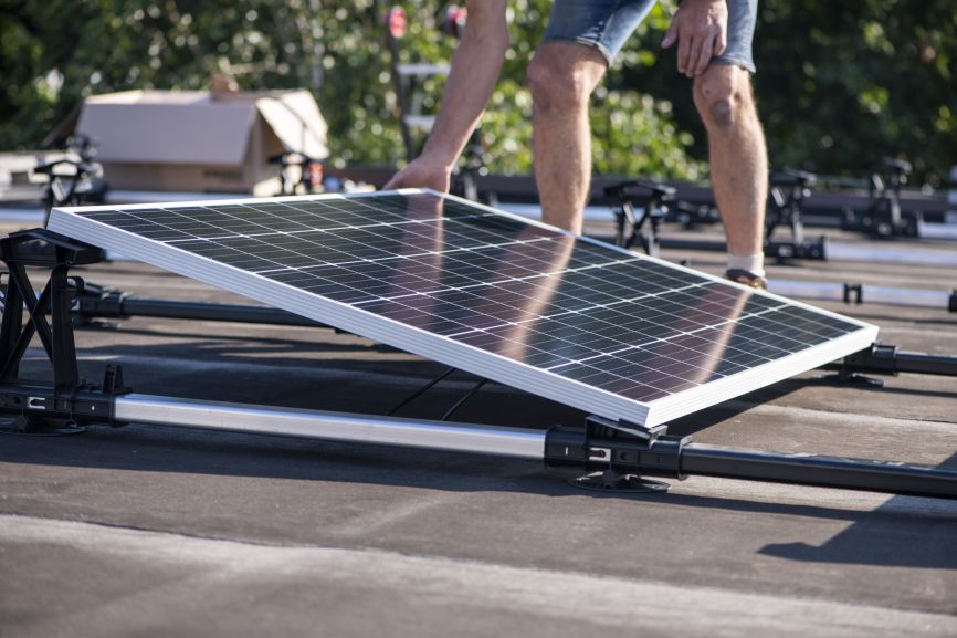 Worker installing solar panel on flat roof – Can You Install Solar Panels on a Flat Roof? by Eco Sun Works