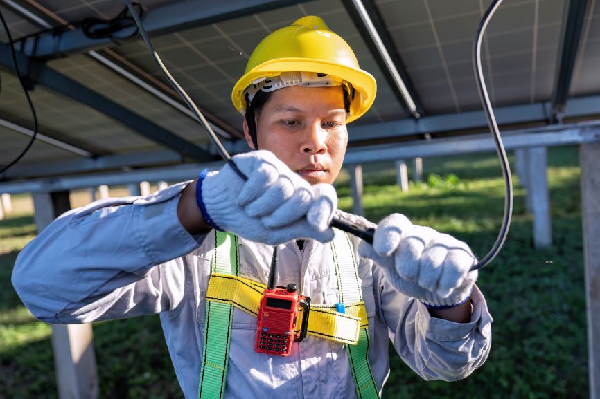 Technician wiring solar panels with safety gear and helmet