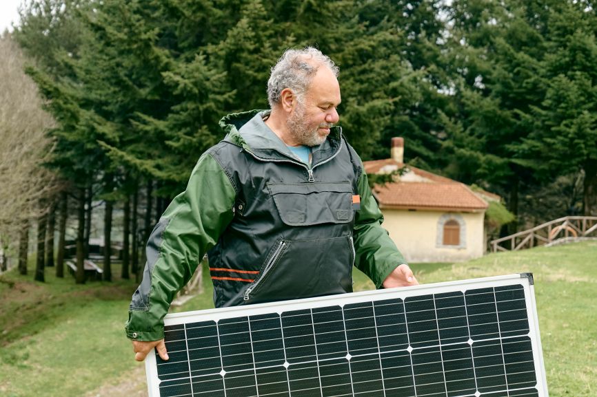 Technician installing EcoSunWorks solar panel system without battery near a countryside home.
