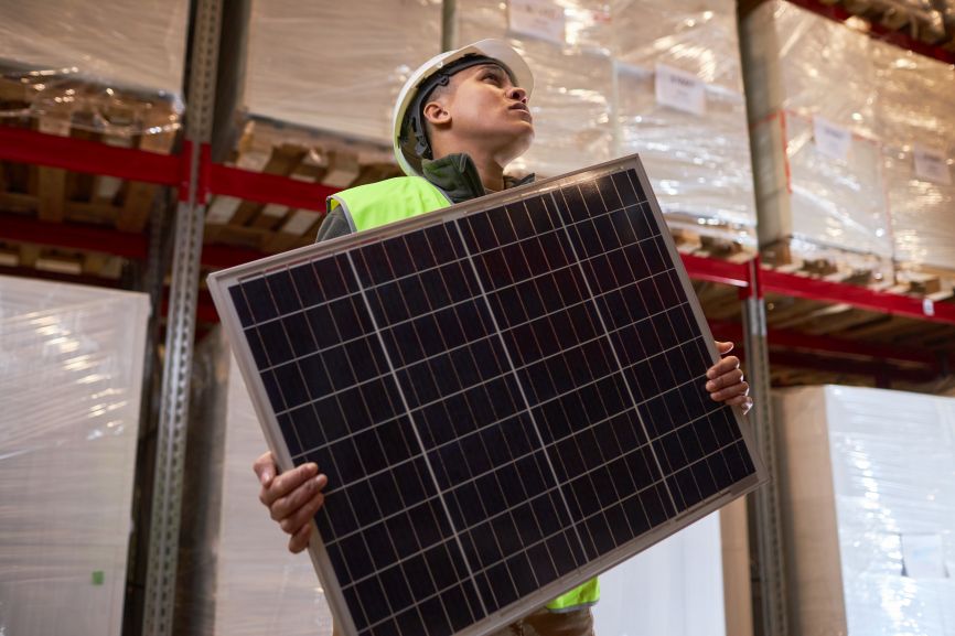 EcoSunWorks technician holding a lightweight solar panel in a warehouse, showcasing the efficiency and portability of modern Lightweight Solar Panels.
