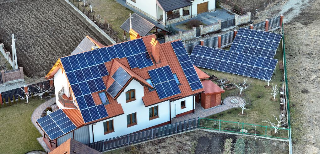 Aerial view of an EcoSunWorks solar-powered home with rooftop and ground-mounted panels illustrating system efficiency for the question, Do Solar Panels Work in the Shade?